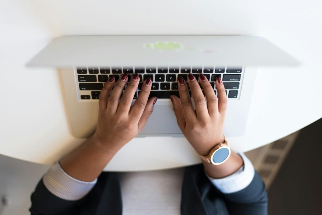 Woman's hands typing on a wireless laptop at a modern office desk, highlighting technology in business.